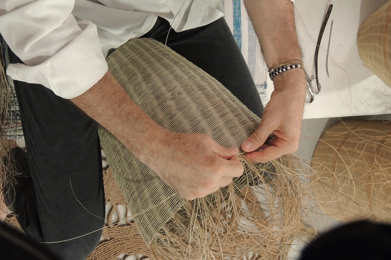 Las manos de Joaquín entrelazan las fibras de esparto en su taller, con la pieza y las herramientas originales